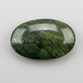 A polished oval green stone with natural marbled veining, resting on a plain white surface by J.W.H. Designs.